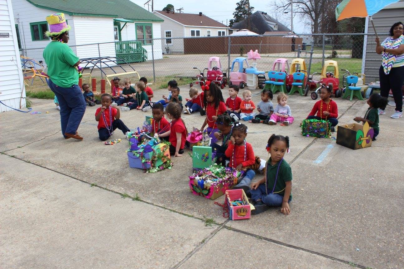 Adults and children sitting on the ground outdoors with colorful boxes