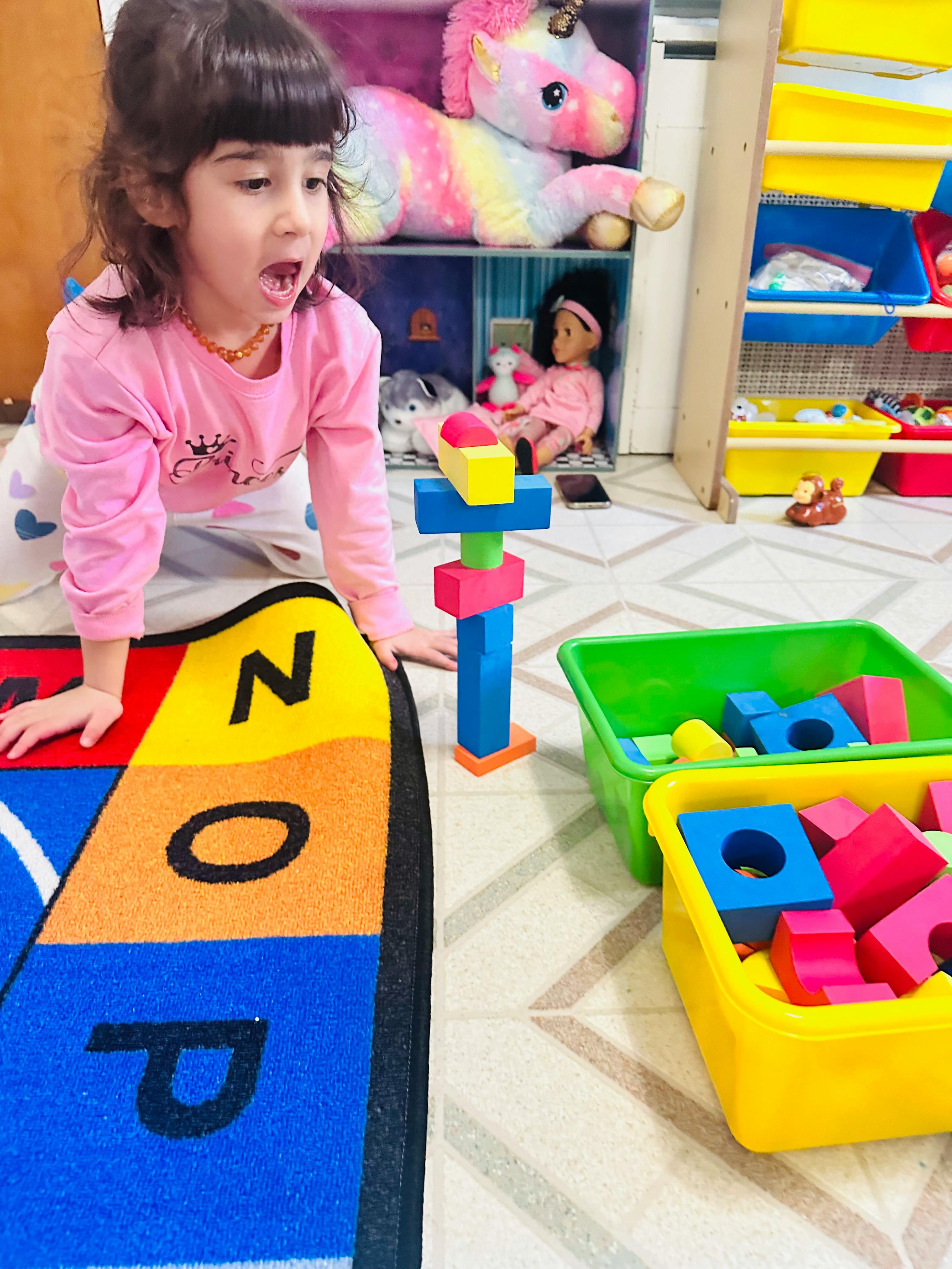 Child on hands and knees next to a colorful block tower