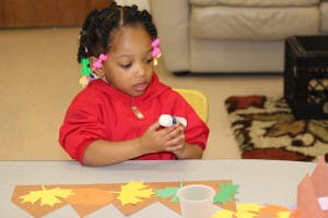Child at a table holding a small object