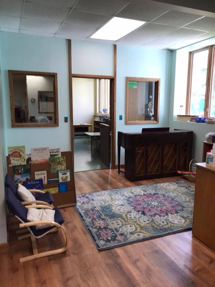 Room with a patterned rug, a wooden chair, and a piano