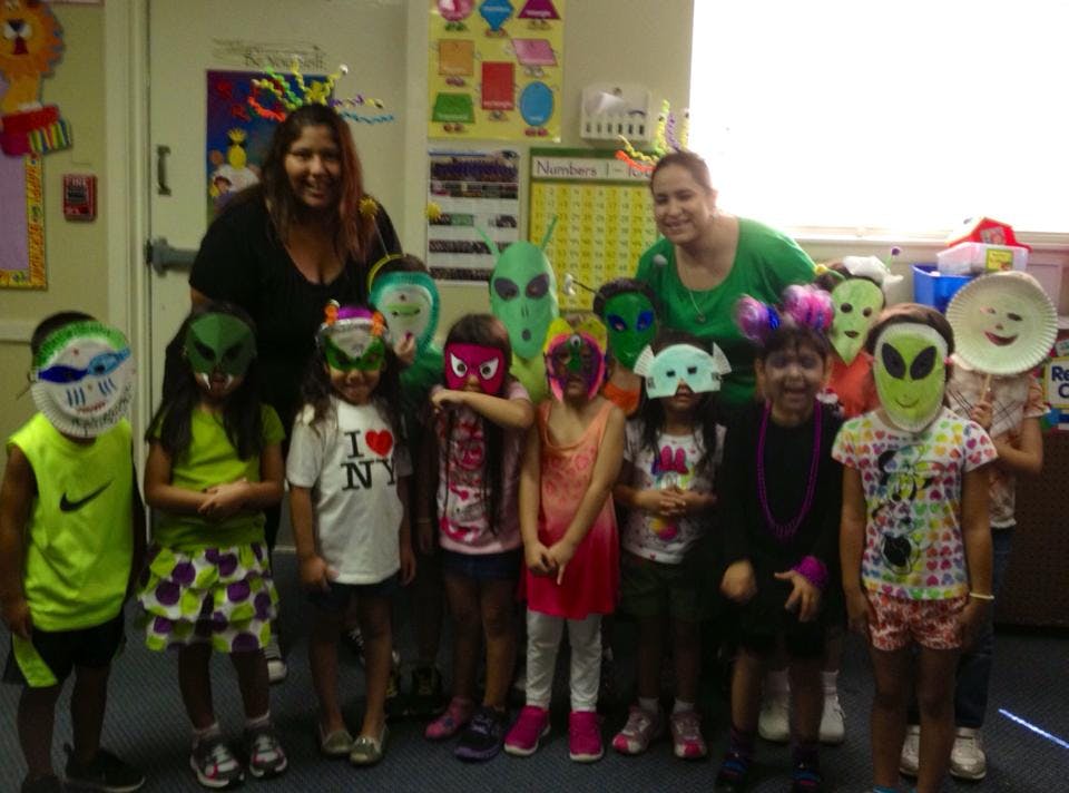 Two people with a group of children wearing masks