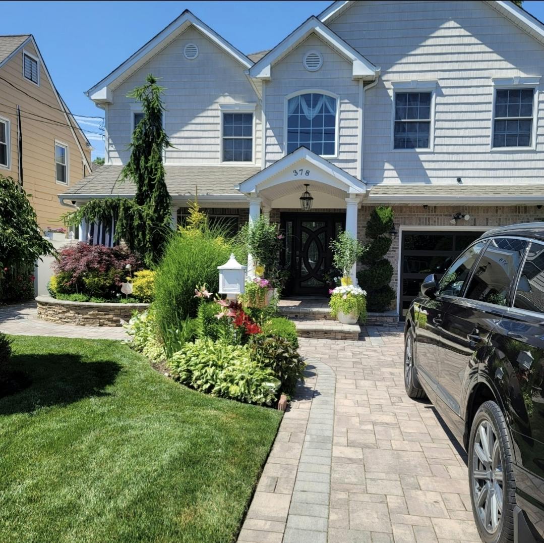 House with a paved driveway and walkway, landscaping, and a parked car