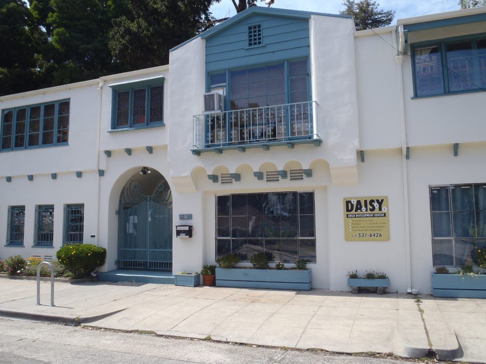 White building with blue trim and a sign that reads "DAISY"