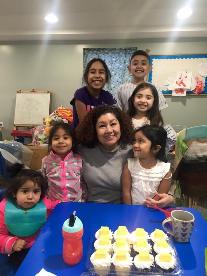 Adult and children posing for a photo with cupcakes on a table