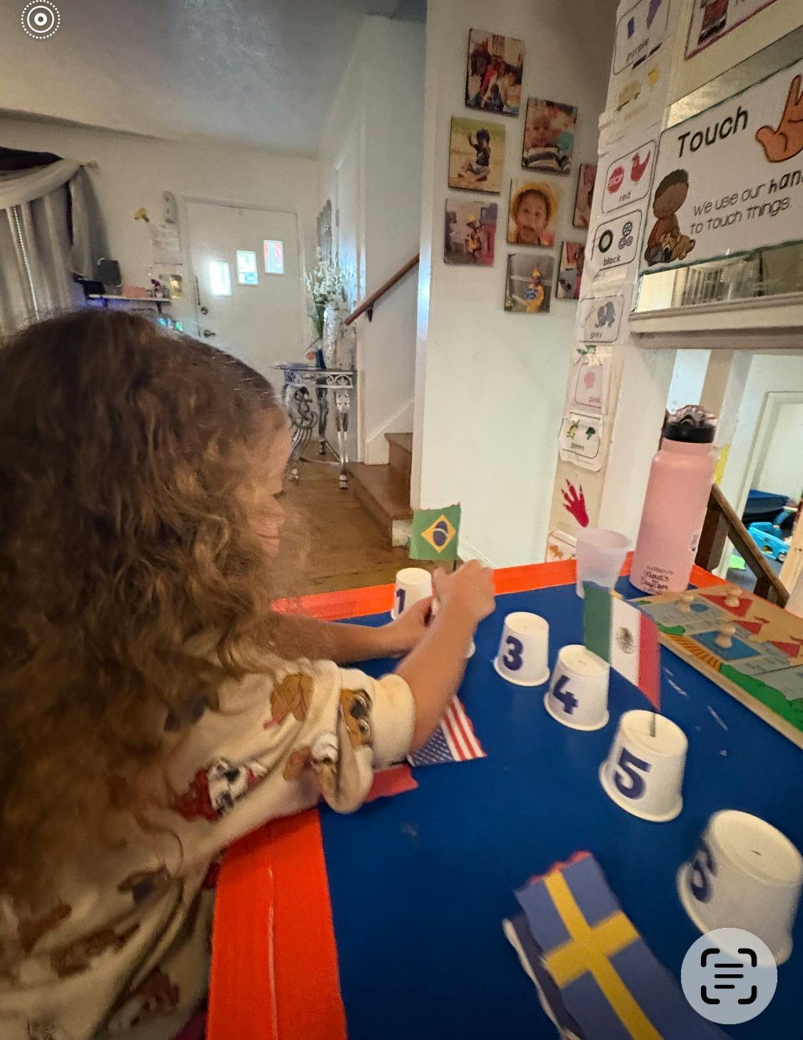 Child playing with numbered cups and small flags on a table