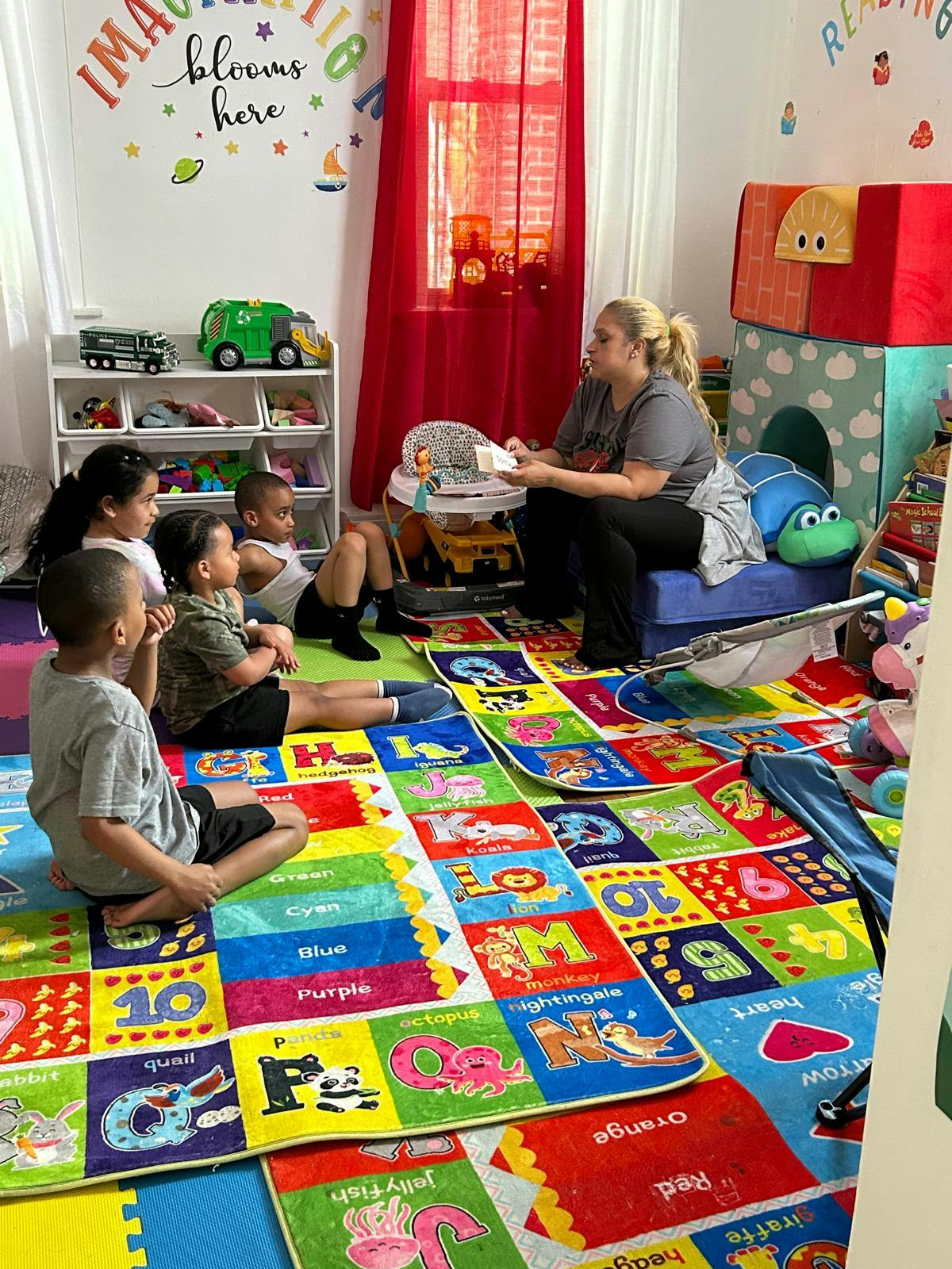 Adult sitting on a blue cushion, reading to four children