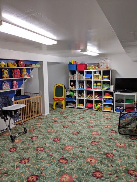 Playroom with shelves of toys, a crib, and a high chair