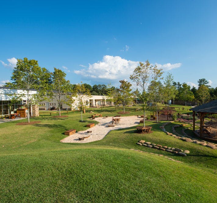 Outdoor playground with sand area, wooden structures, and green grass