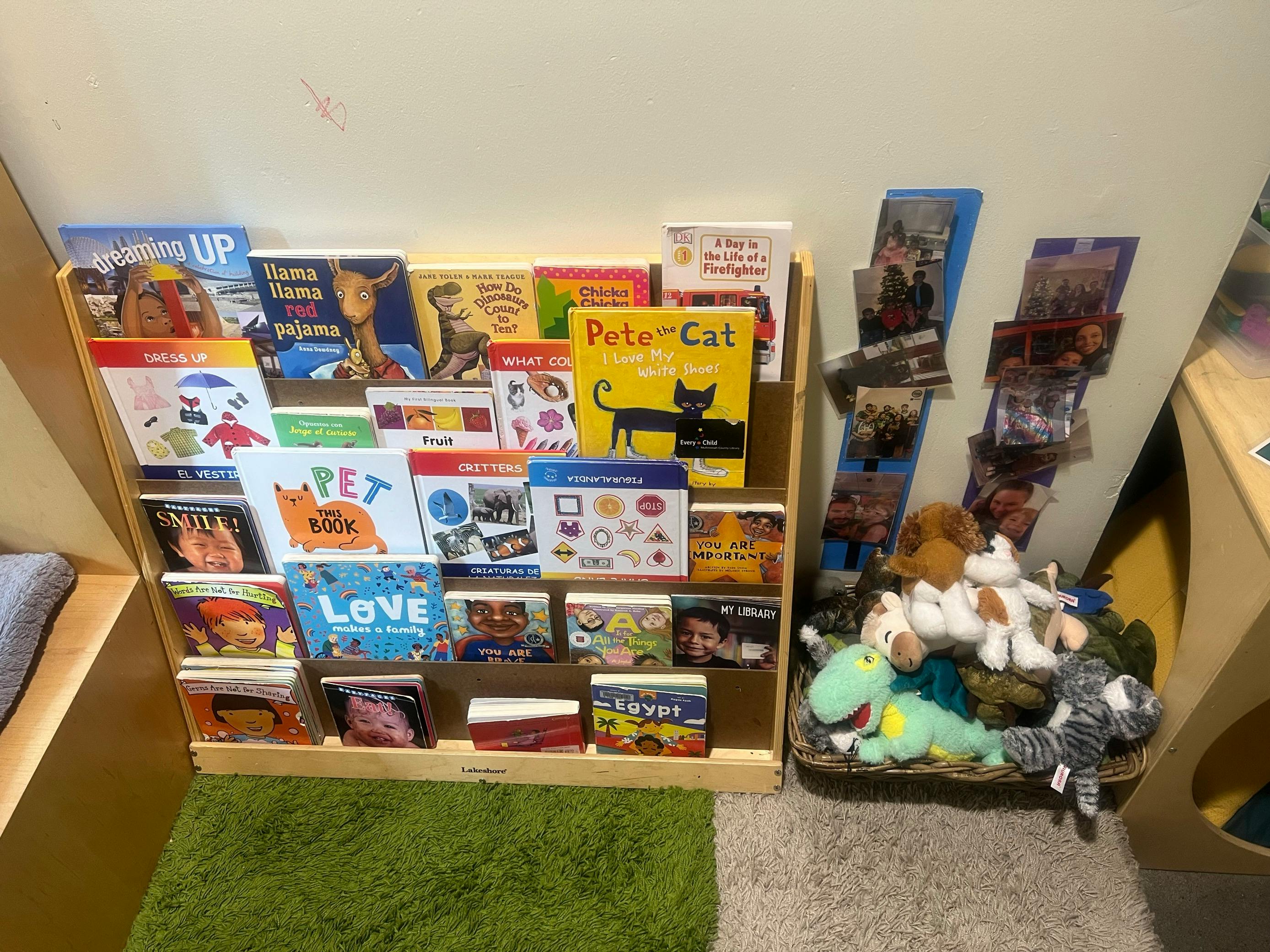 Children's books displayed on a wooden shelf next to a basket of stuffed animals