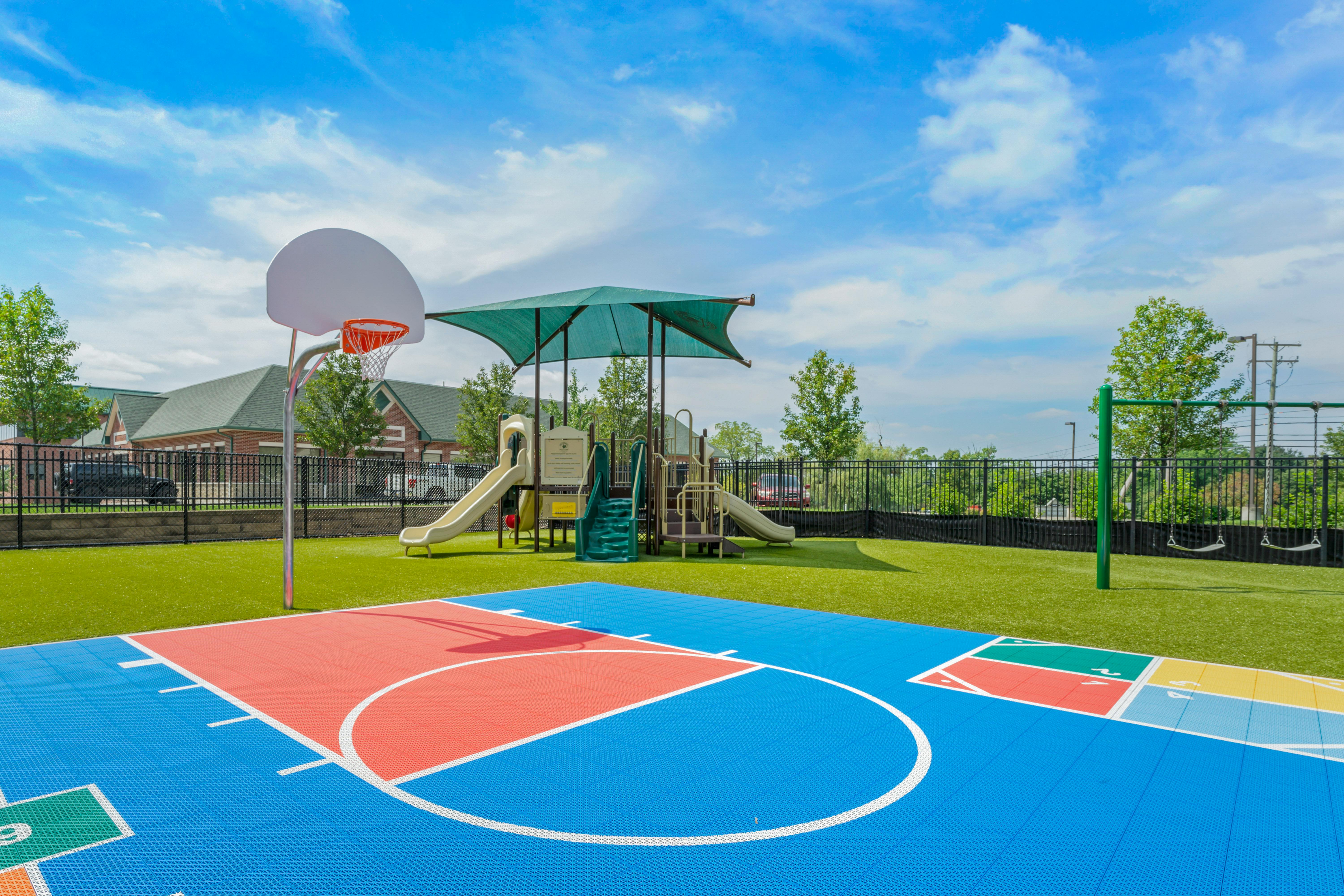 Basketball court and playground area with swings and slide