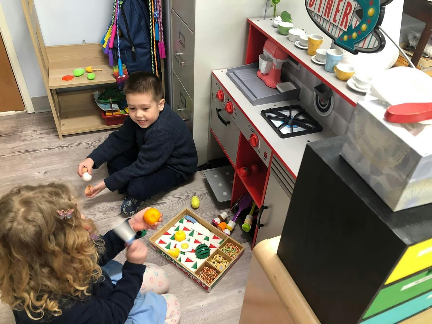 Two children playing with toy food on the floor