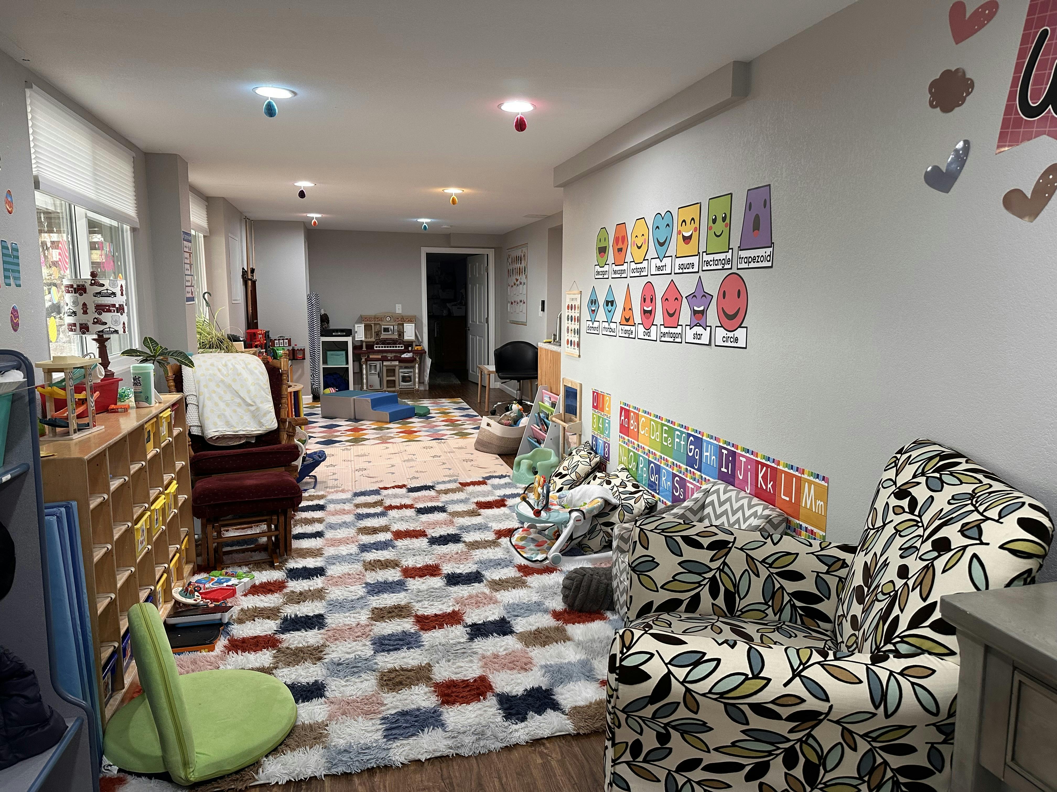 Children's playroom with colorful rugs, cubbies, play kitchen, and alphabet wall charts