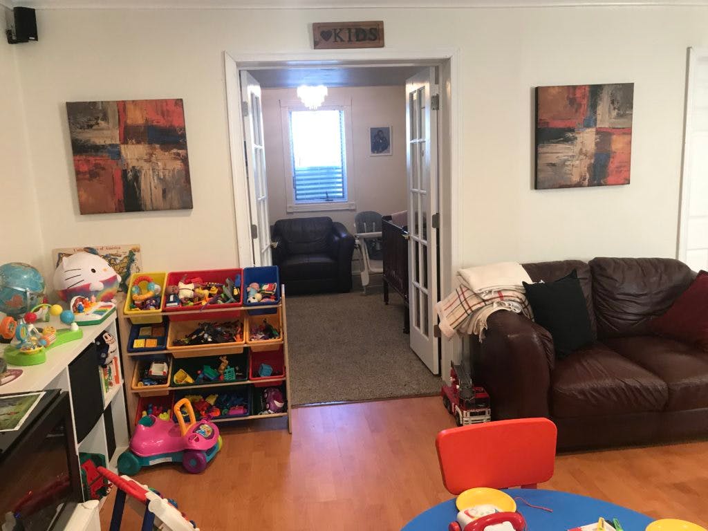 Living room with a brown couch, toy organizer, and open french doors