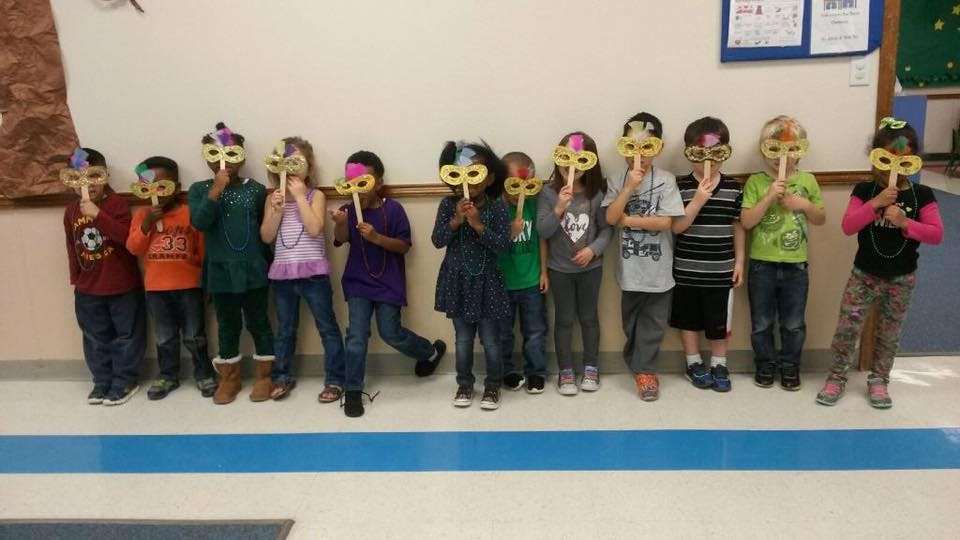 Group of children holding masks over their faces