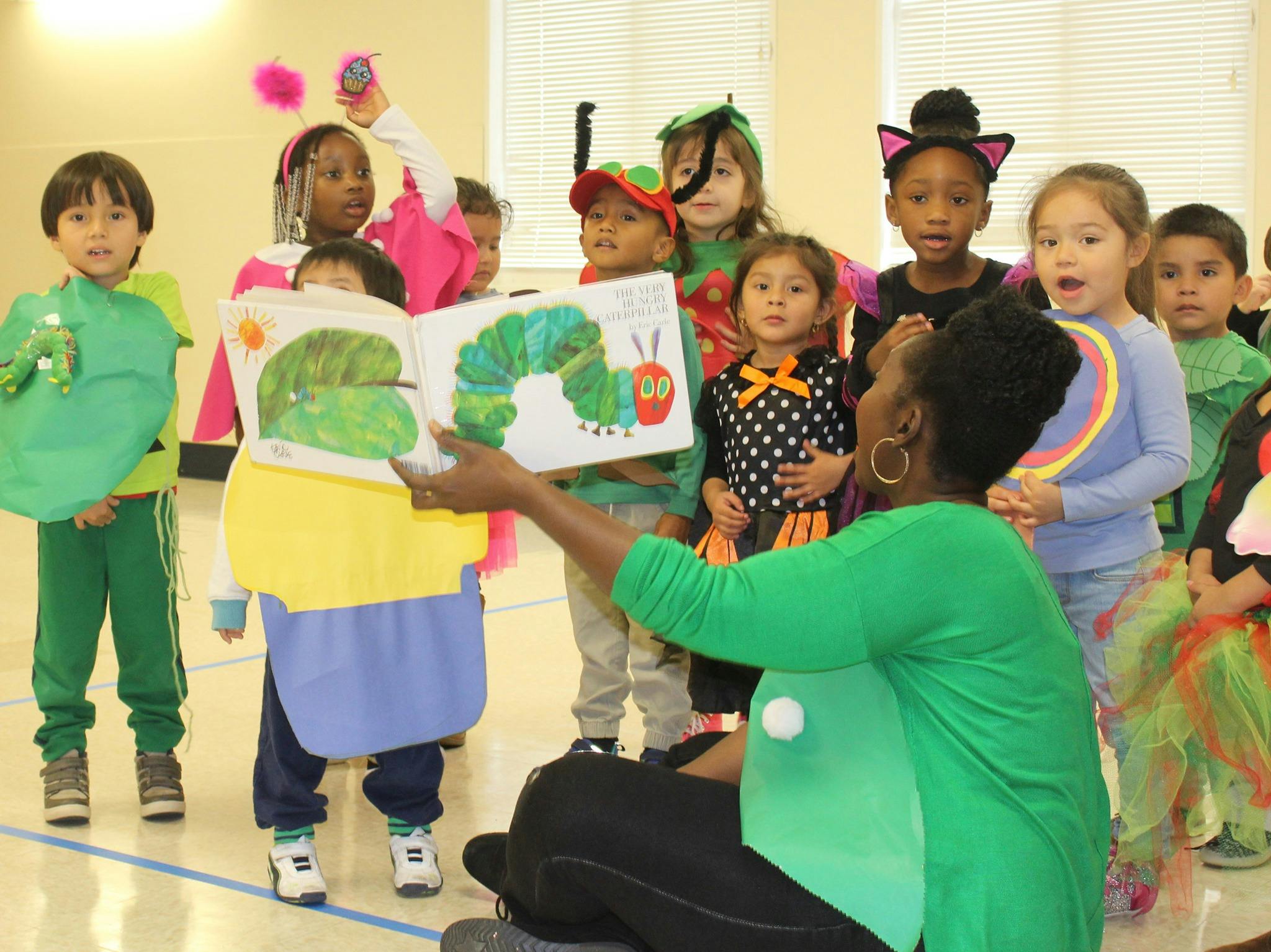 Adult reading "The Very Hungry Caterpillar" to a group of children