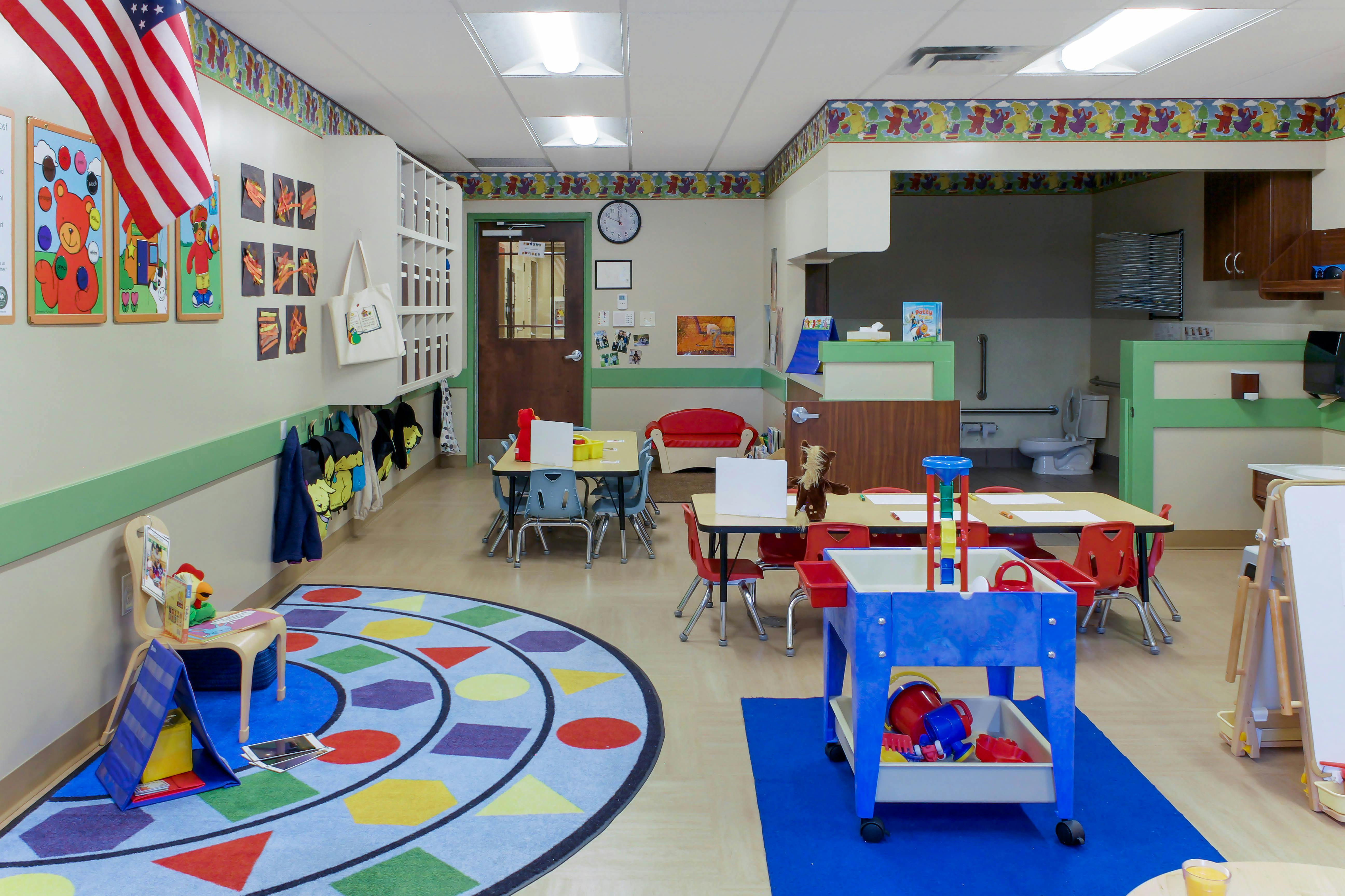 An empty early childhood classroom with small tables and chairs