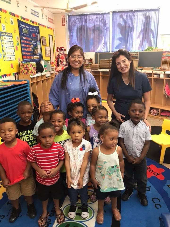 Two people and a group of children in a classroom