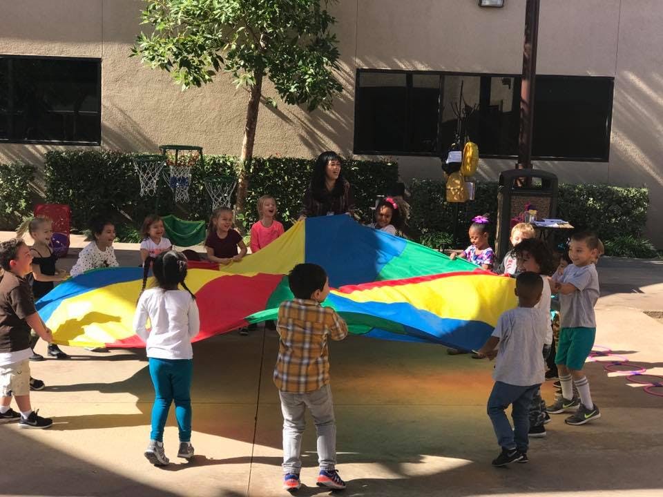 Children playing with a colorful parachute outdoors