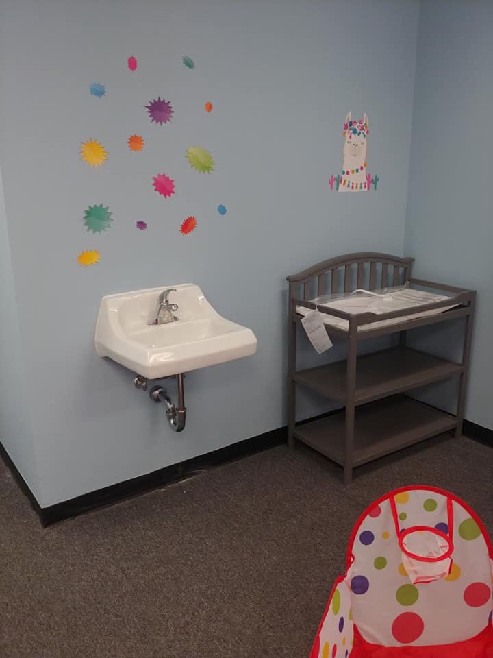 Wall-mounted sink next to a changing table with shelves