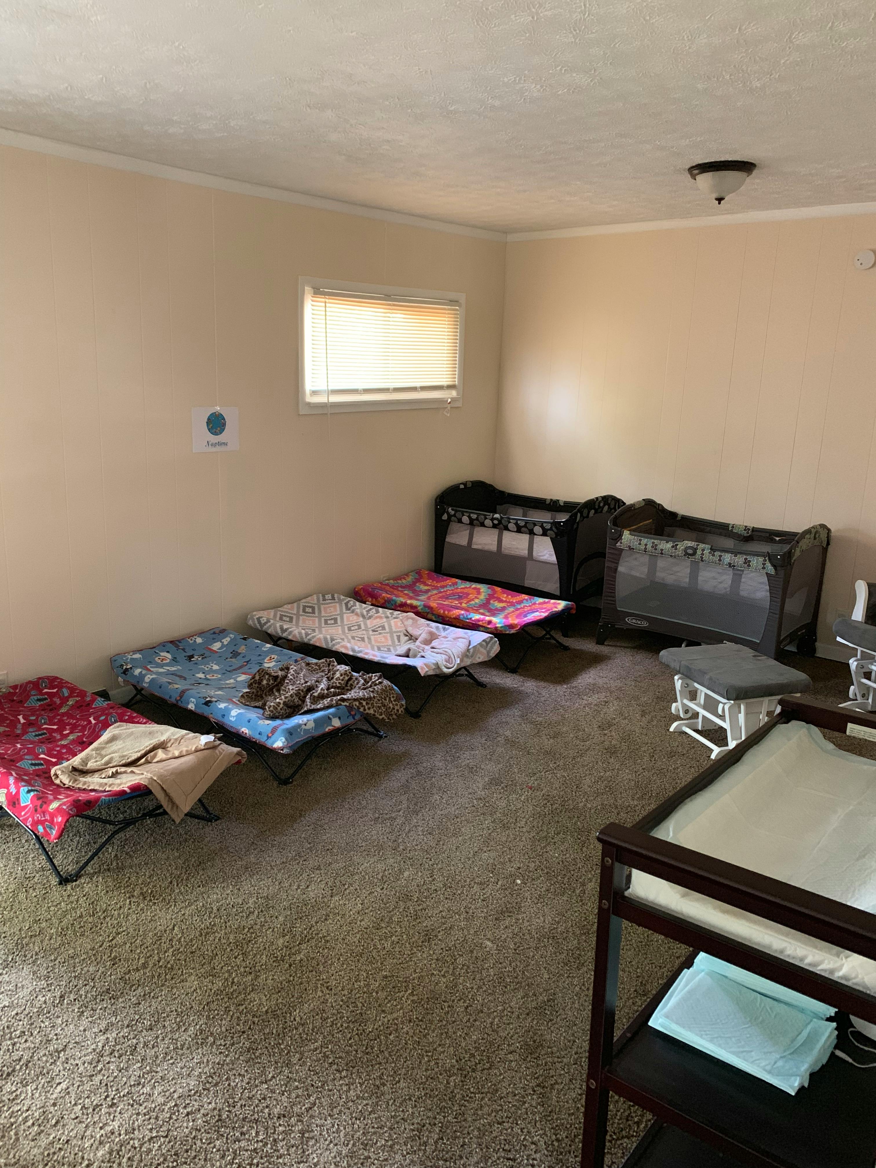 Room with several cots and two portable cribs