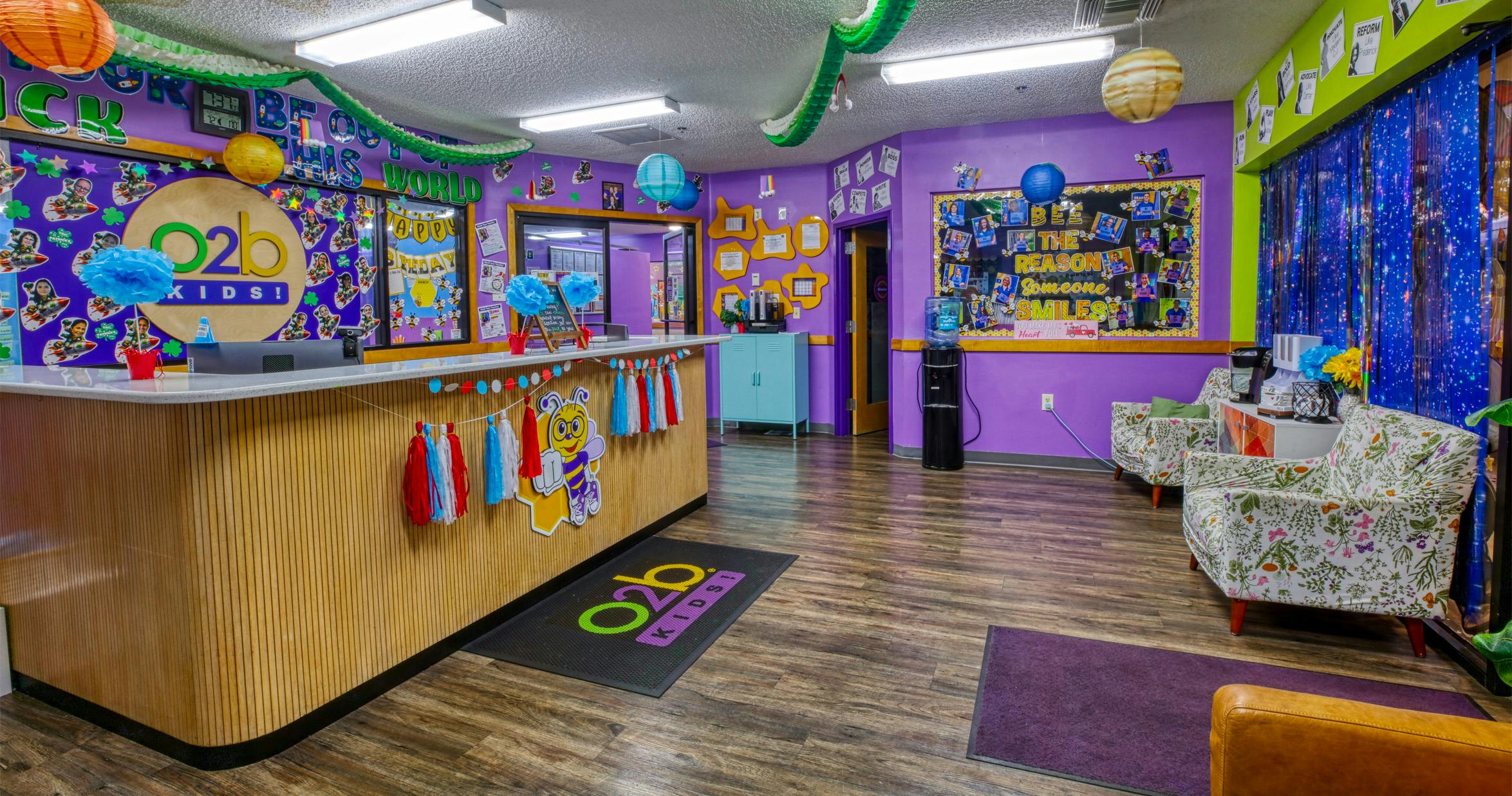 Reception area of a children's learning center with a wooden front desk and bright purple walls