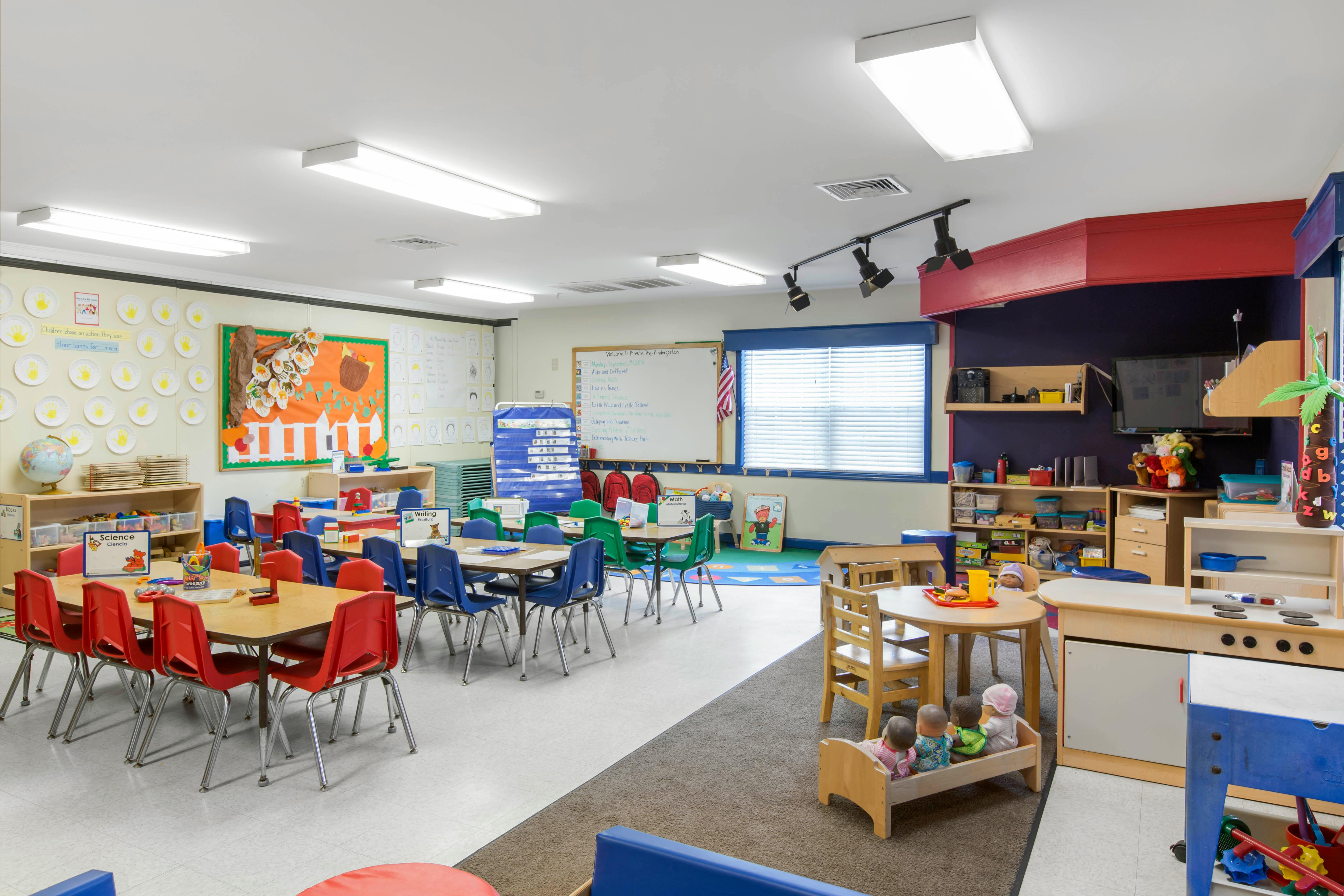 A colorful empty kindergarten classroom with small tables and chairs