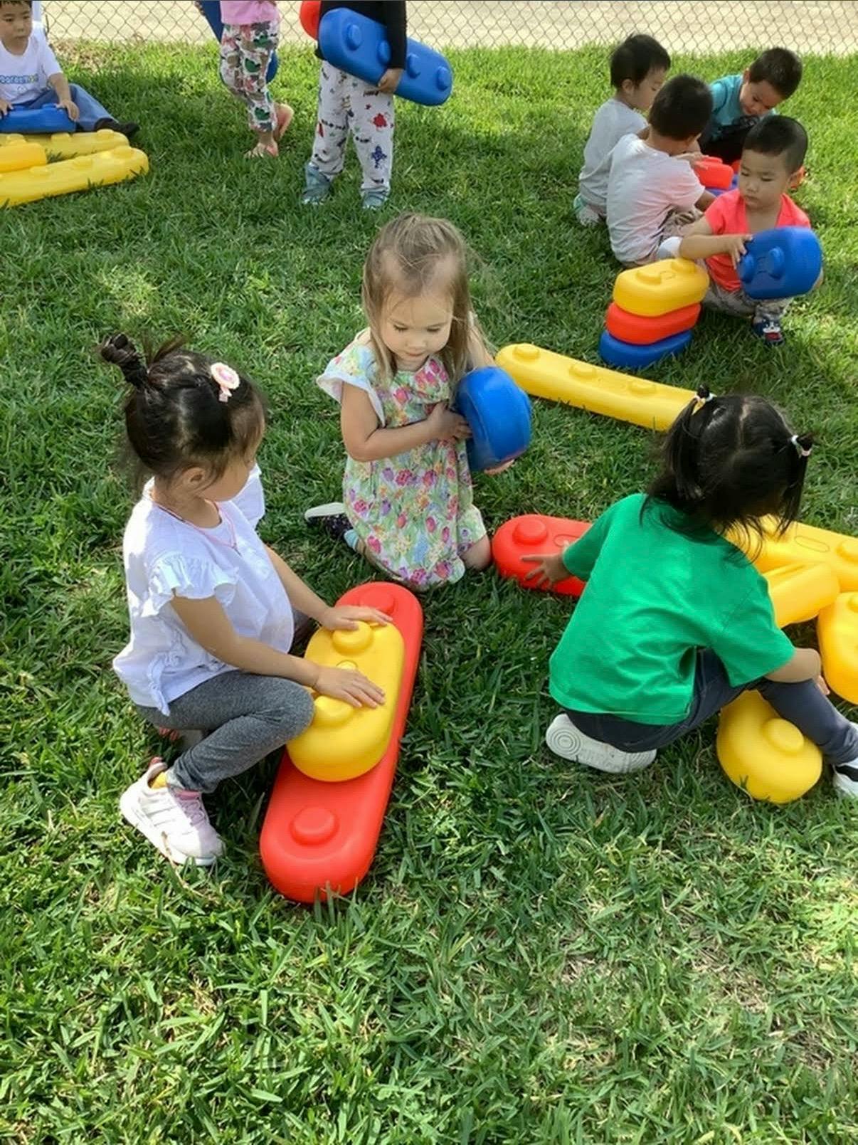 Several children playing with colorful building blocks on a grassy lawn