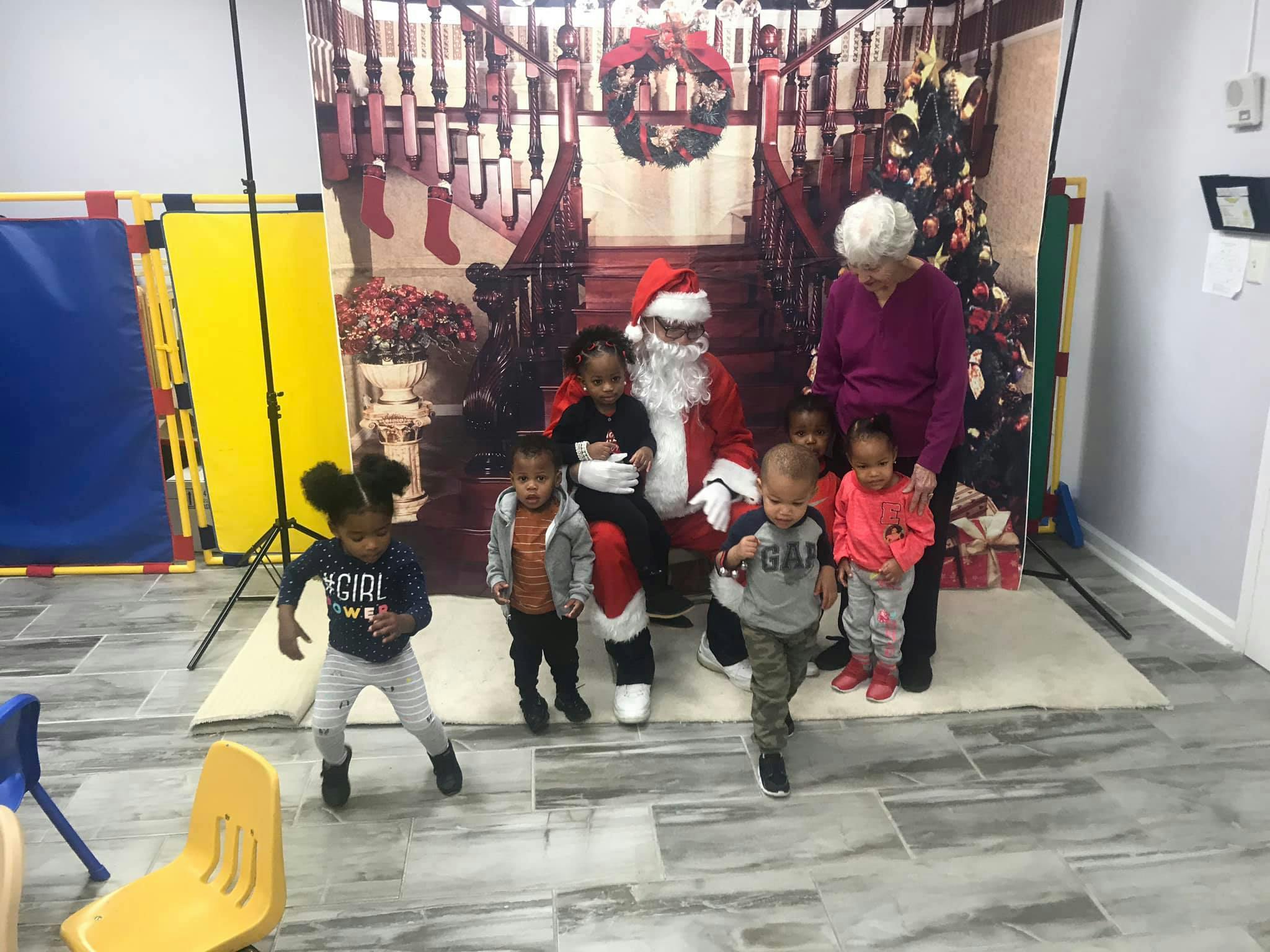 Santa Claus with an adult and several children in front of a holiday backdrop