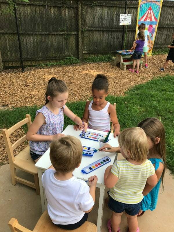 Children painting at a table outdoors