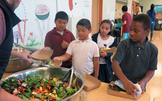 Person serving salad to children