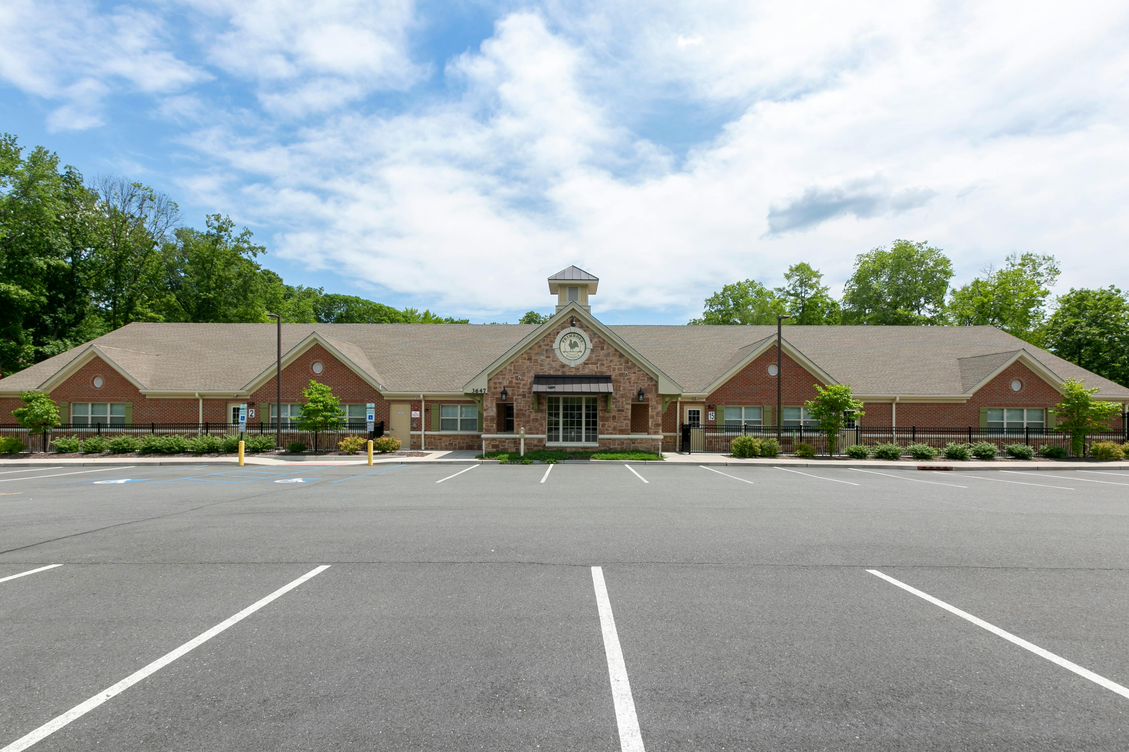 Brick building with a brown roof and a large parking lot in front