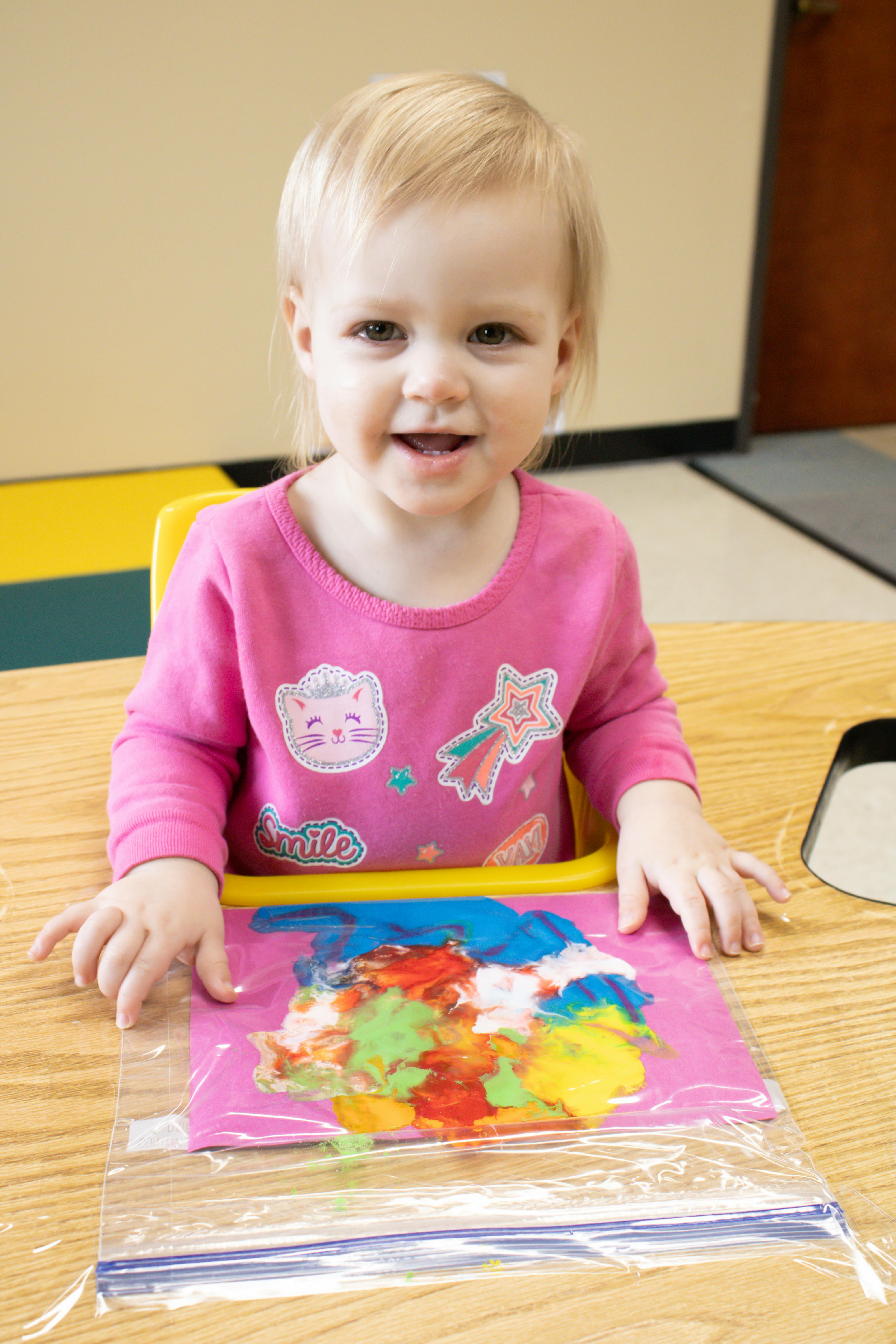 Child sitting at a table with a colorful paint bag