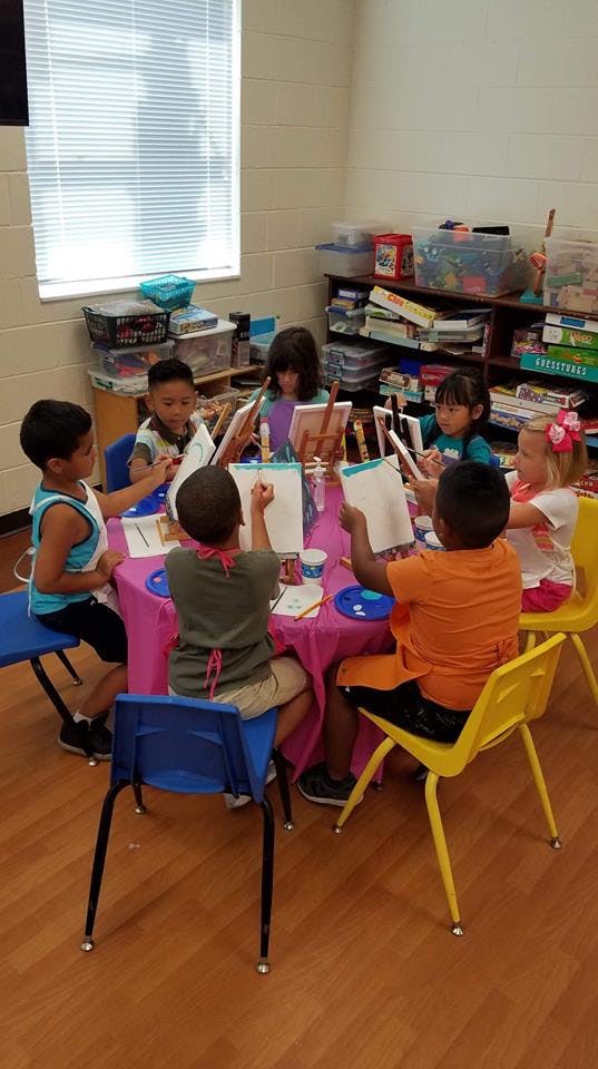 Children painting at a table in a classroom