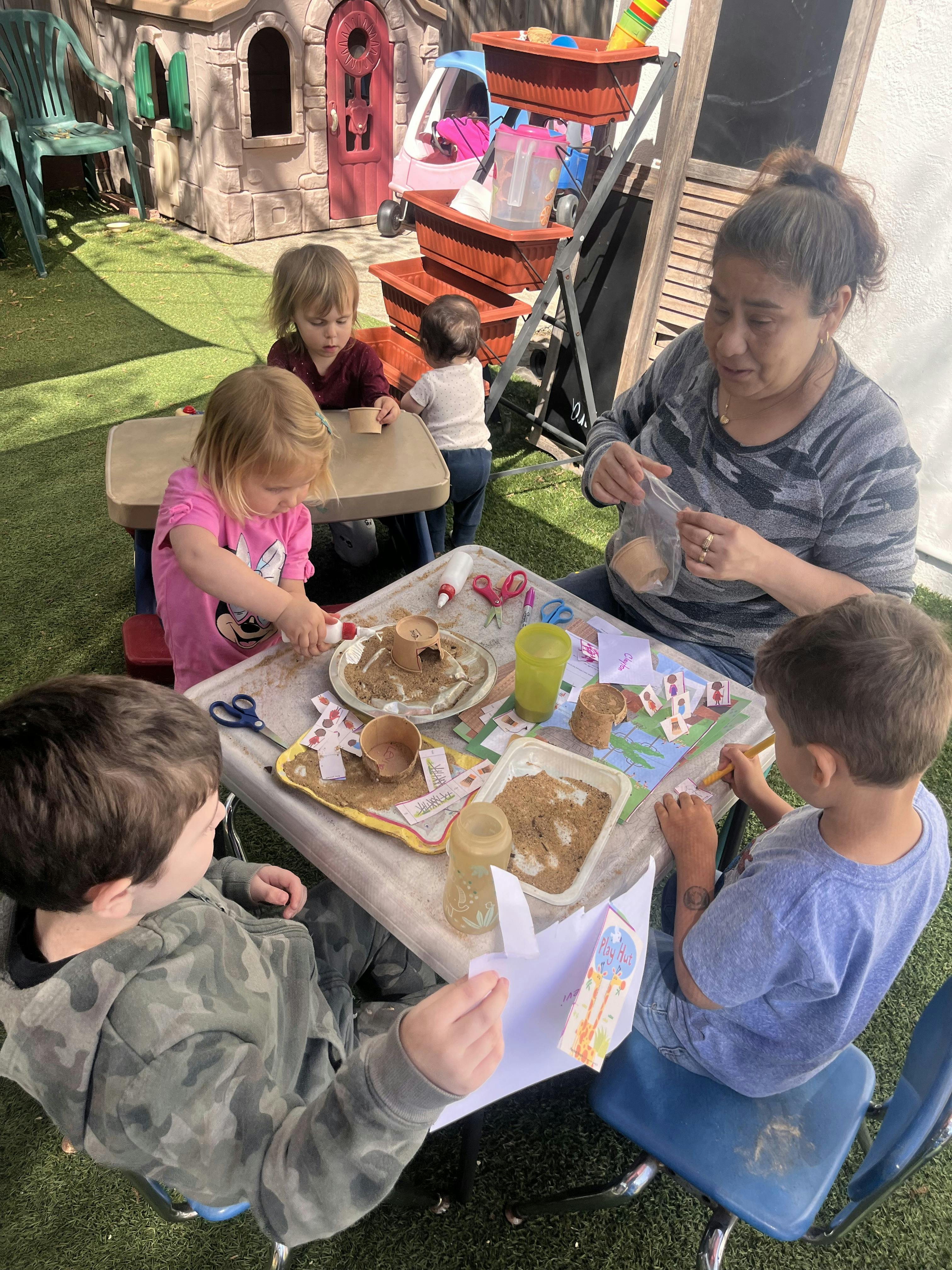 Adult and children doing crafts at tables outdoors