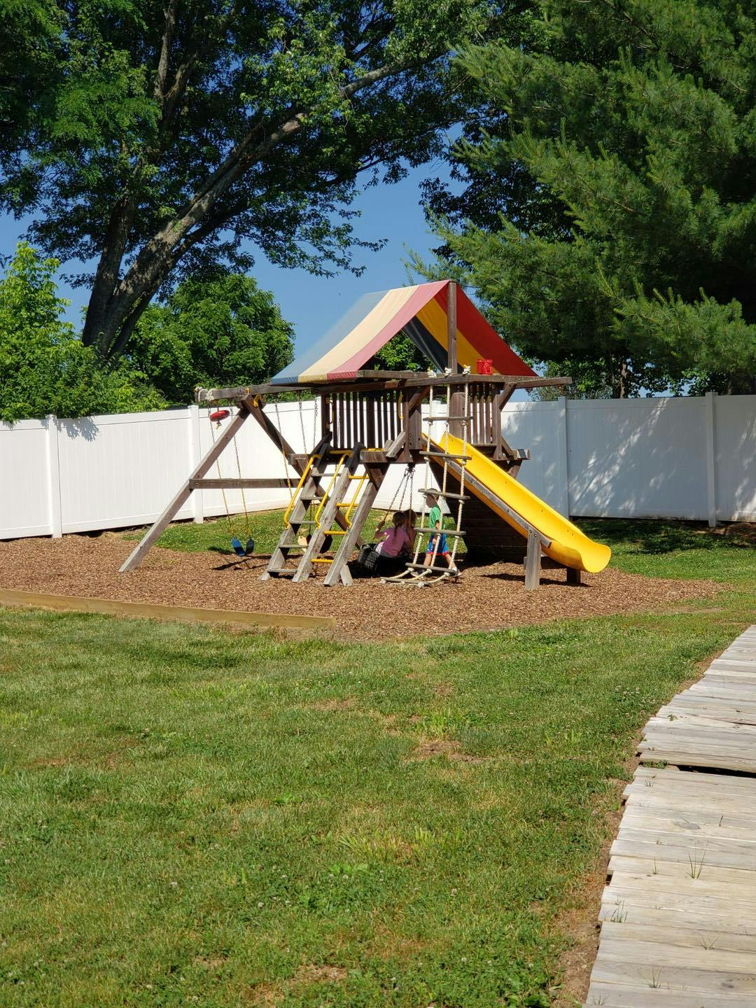 Playground set with a yellow slide and two children sitting underneath