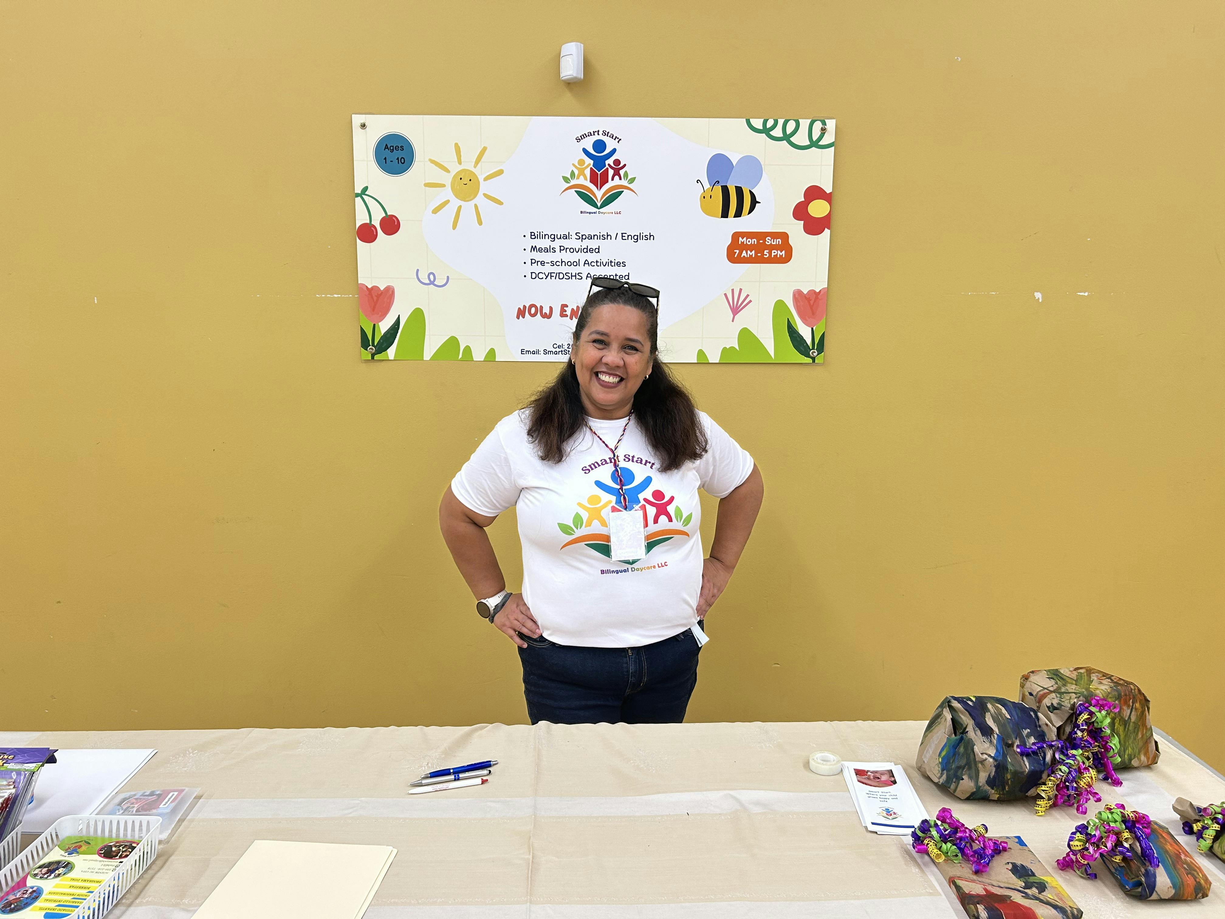 Person standing behind a table with a banner in the background