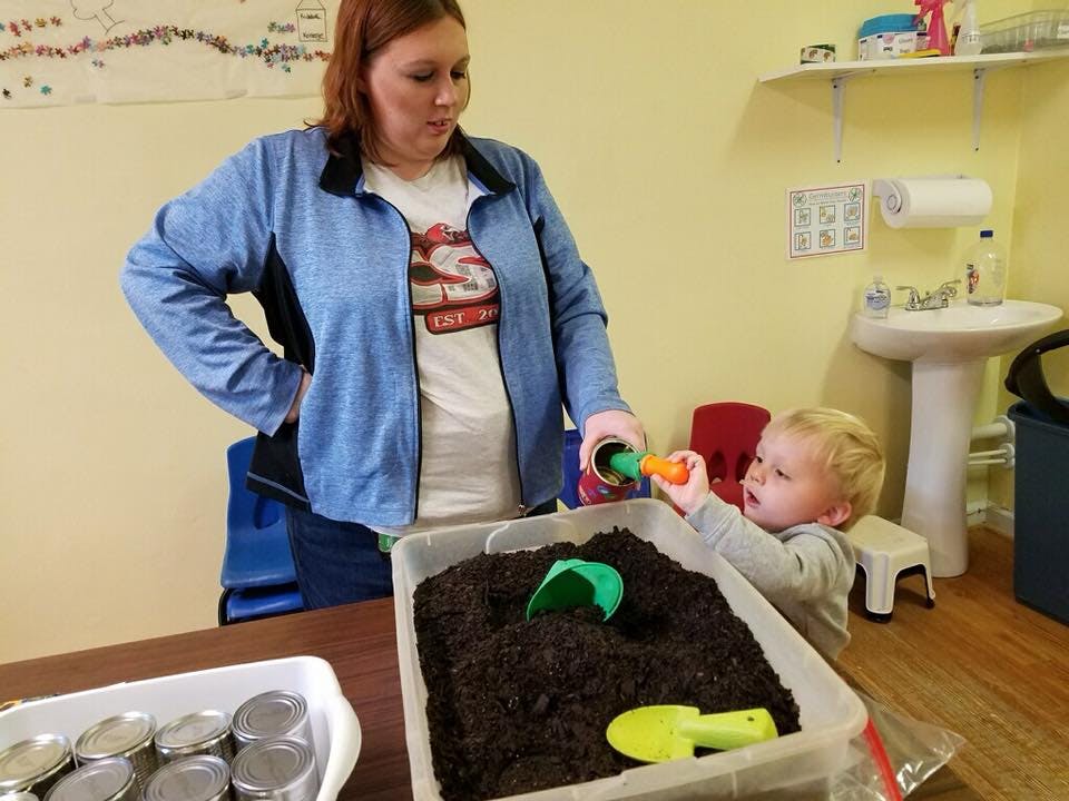 Person and child playing with dirt in a container