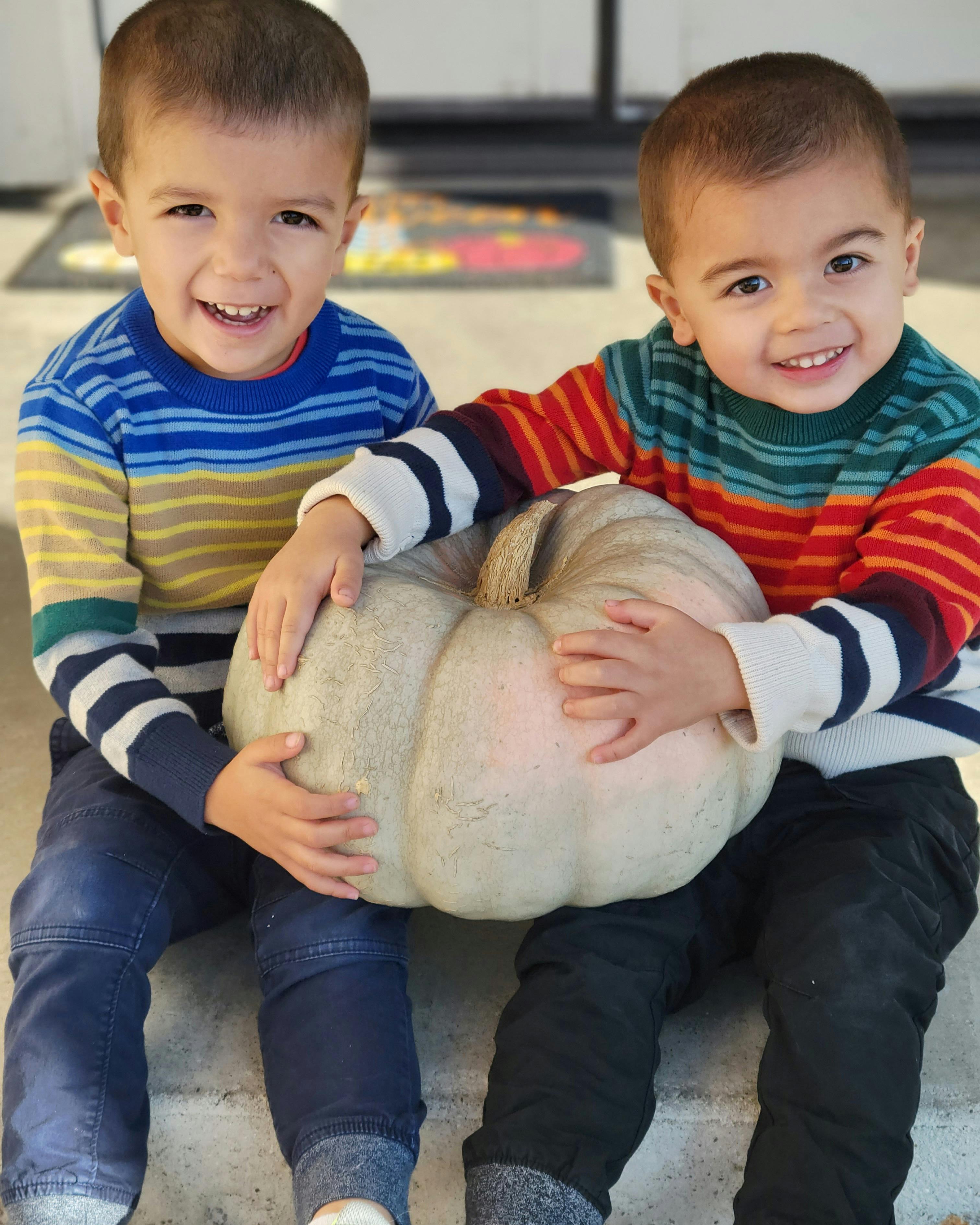 Two children holding a large pumpkin