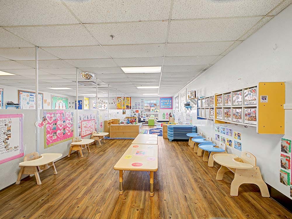 Empty classroom with small tables, chairs, and shelves