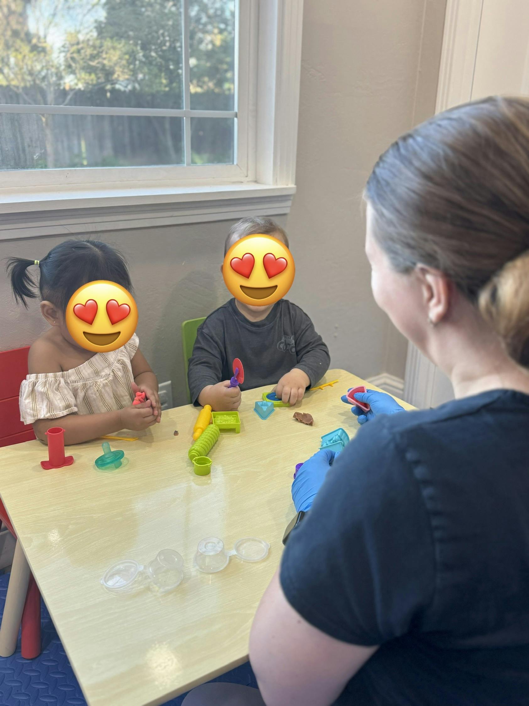 Adult and two children playing with modeling clay at a table