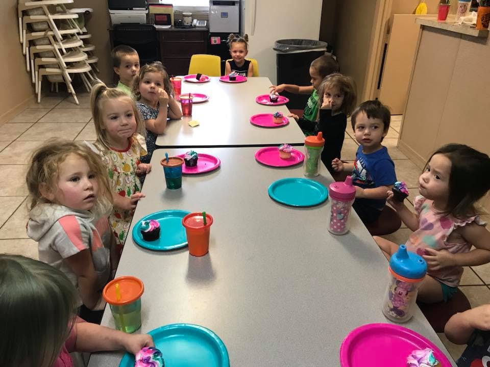 Children sitting at tables with plates and cups