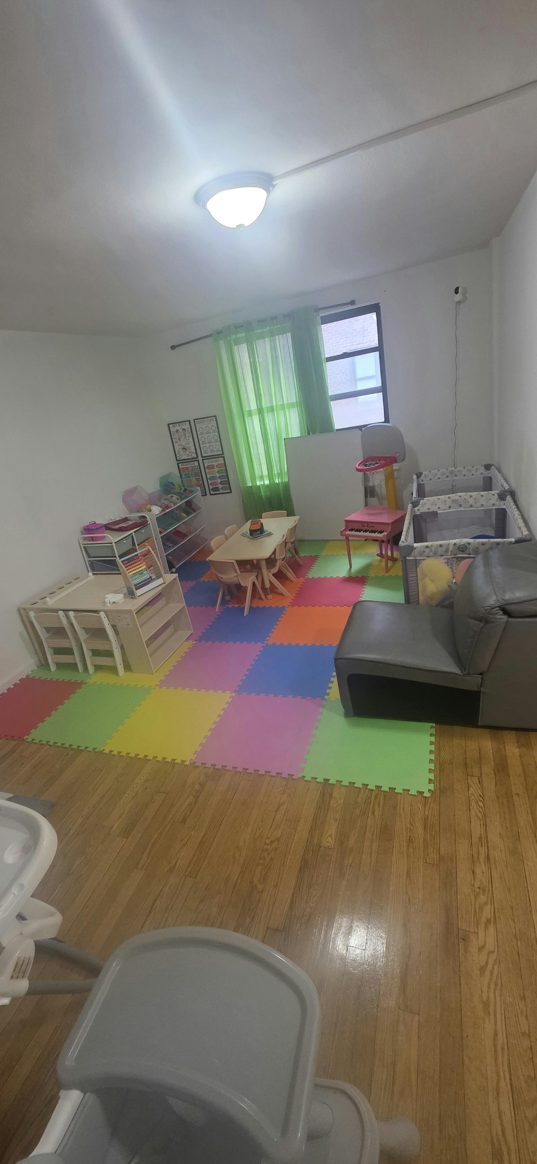 Child playroom with small tables, chairs, and colorful foam floor mats