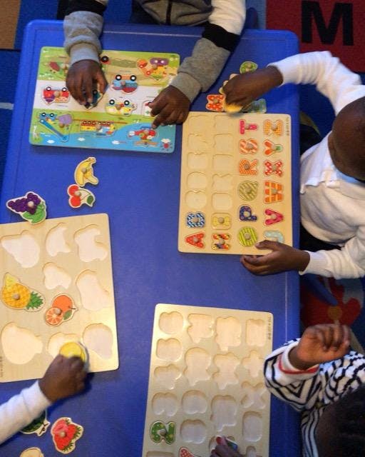 Children playing with wooden puzzles on a blue table