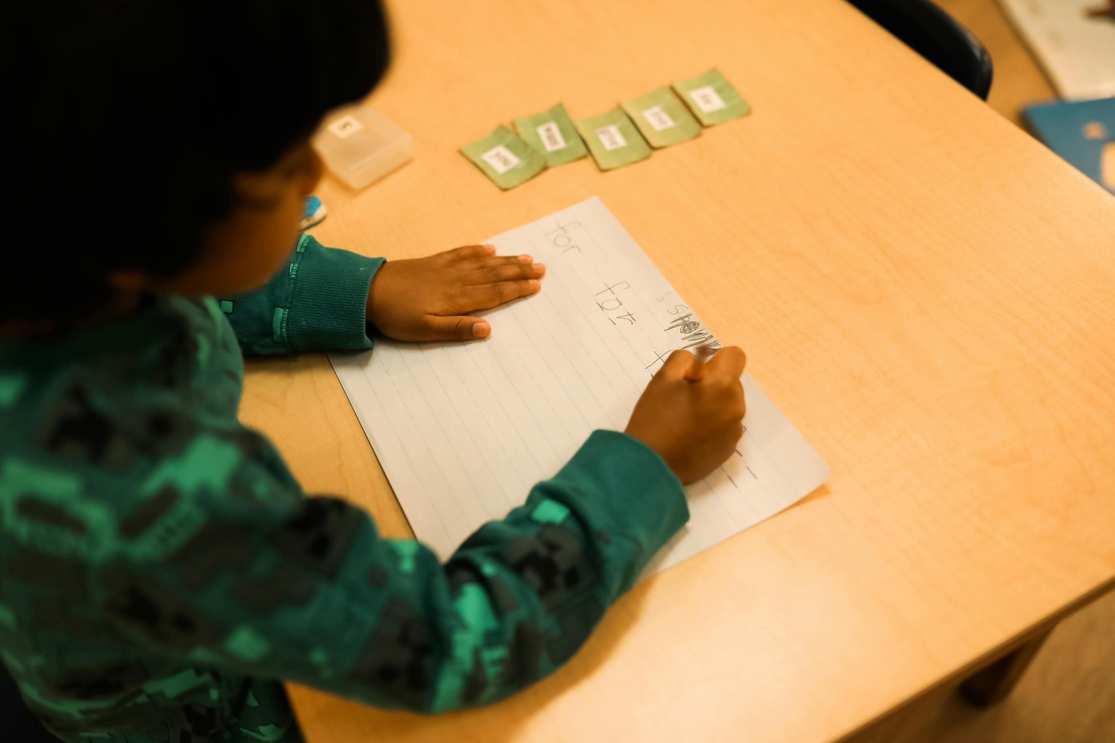 Child writing on paper at a table