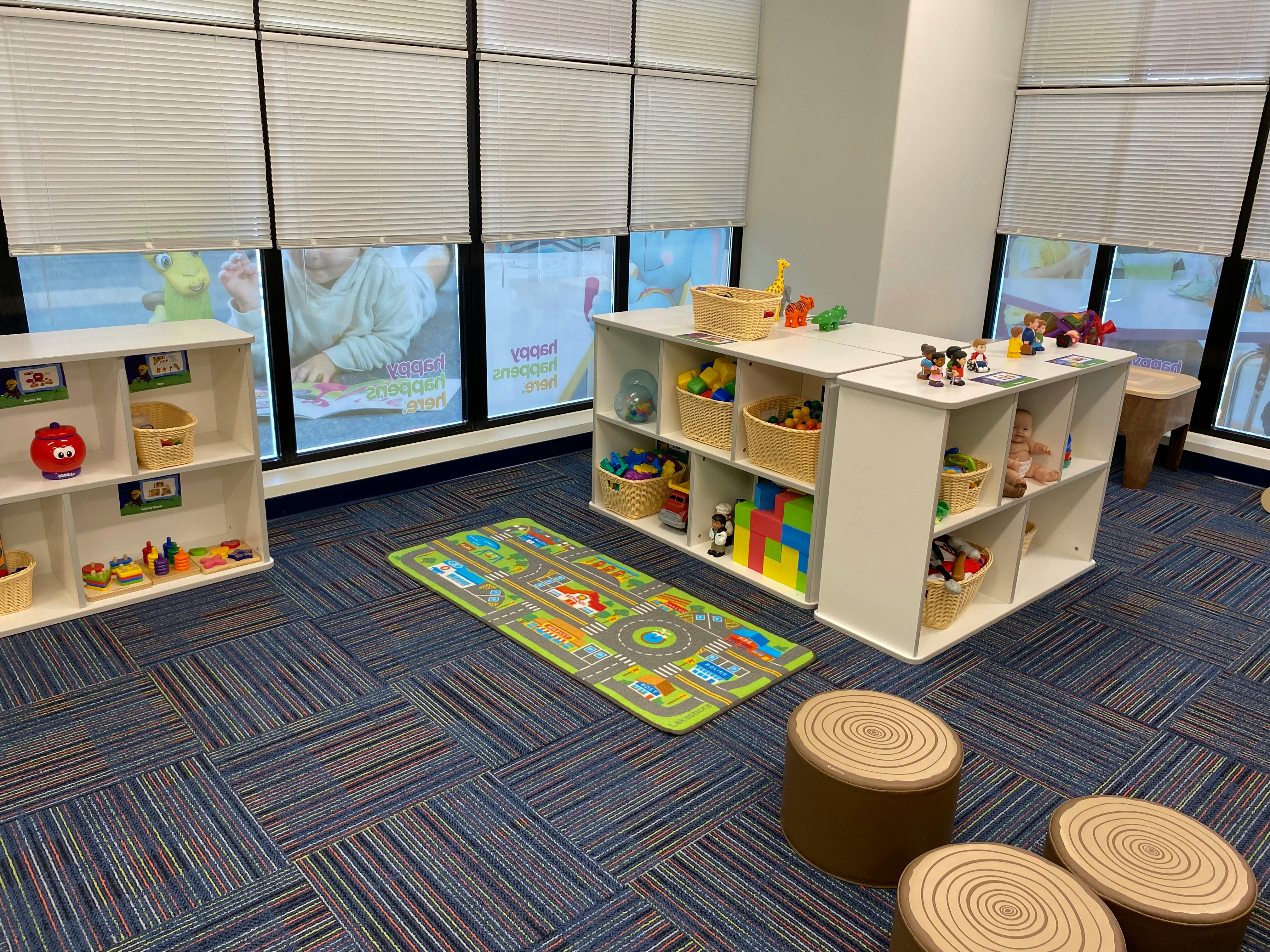 Playroom with shelves of toys, a road map rug, and window blinds