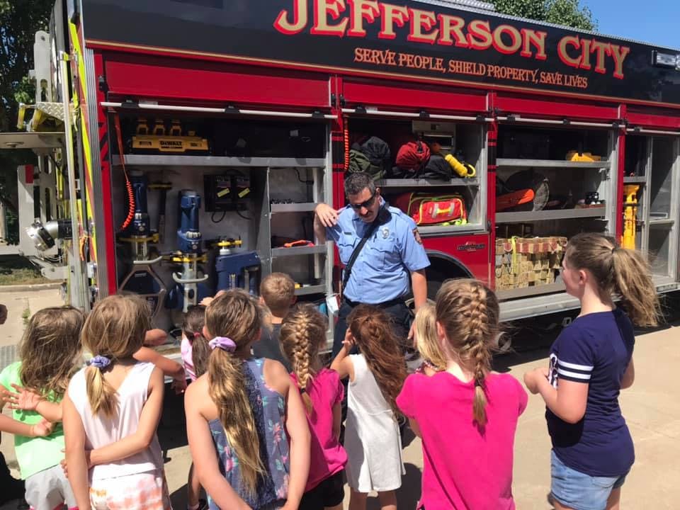 Person in uniform showing children equipment on a fire truck