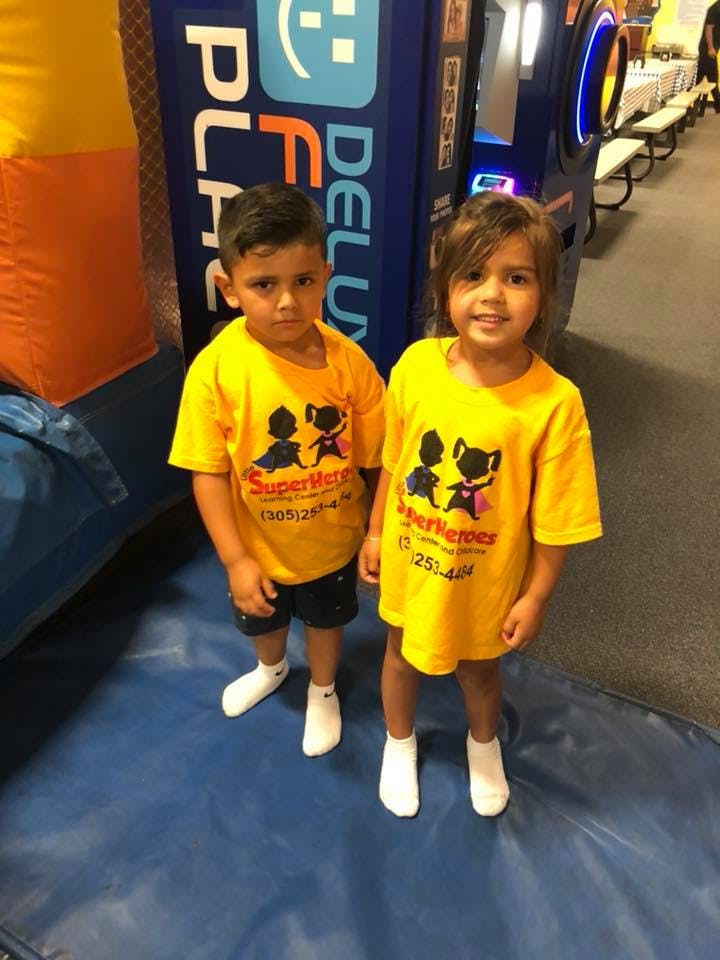 Two children in yellow shirts standing on a blue mat