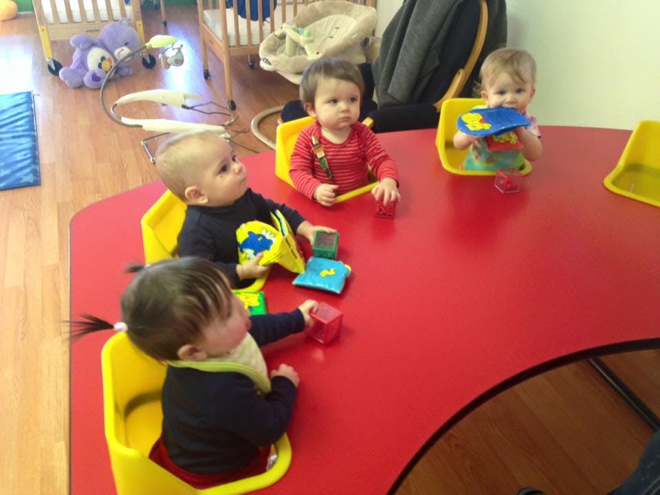 Four children sitting at a red table playing with toys
