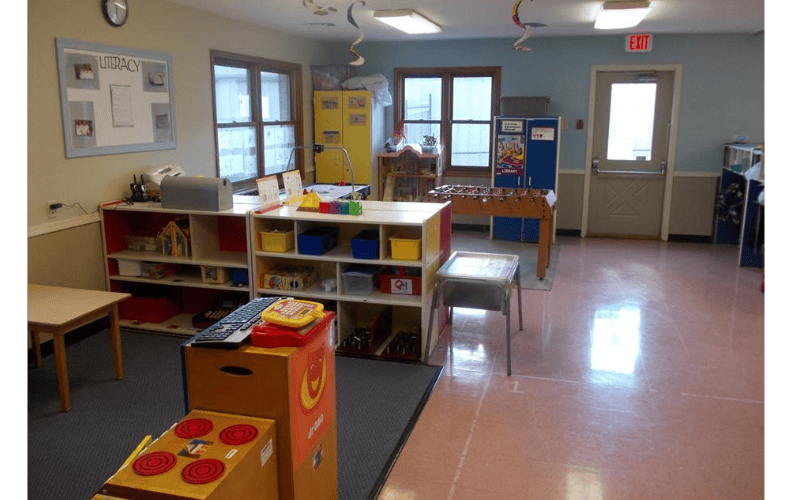 Classroom with shelves, toys, foosball table, and a bulletin board that reads "LITERACY"