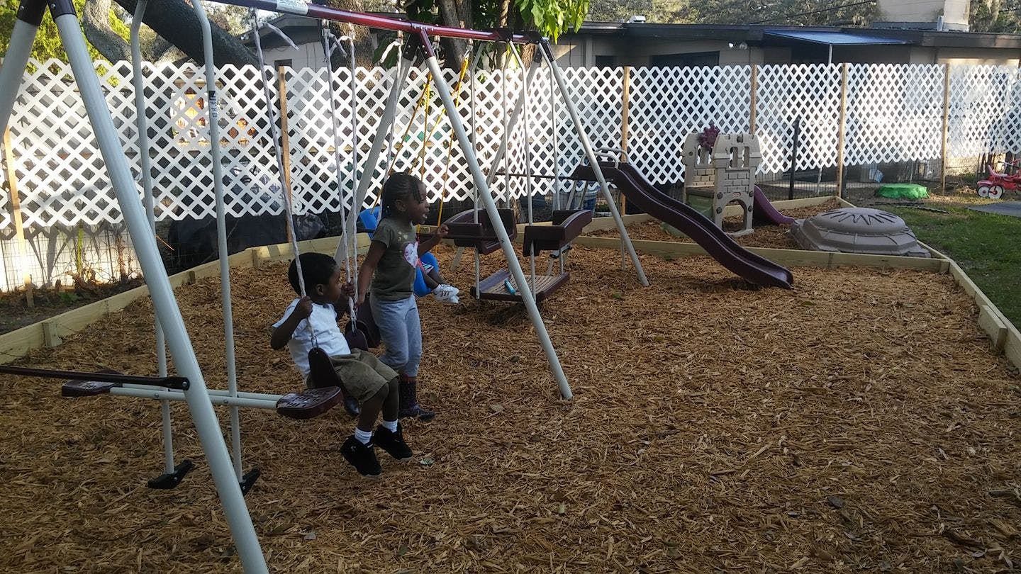 Two children on a swing set in a playground